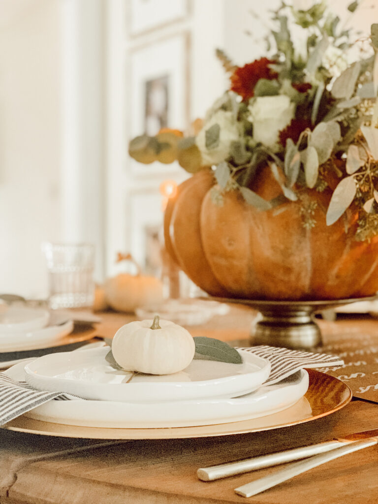 DIY Pumpkin flower arrangment on a fall tablescape with white pumpkins and fall dinnerware.
