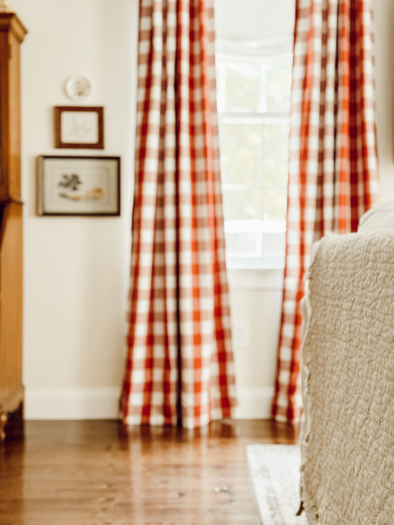 Red gingham curtains and a quilt draped on the back of the couch are some easy decorations for the fall season.