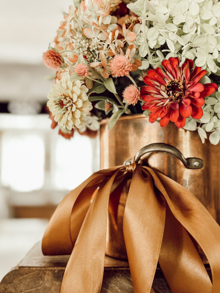 Easy Fall flower arrangement in a copper pot tied with a copper satin ribbon.