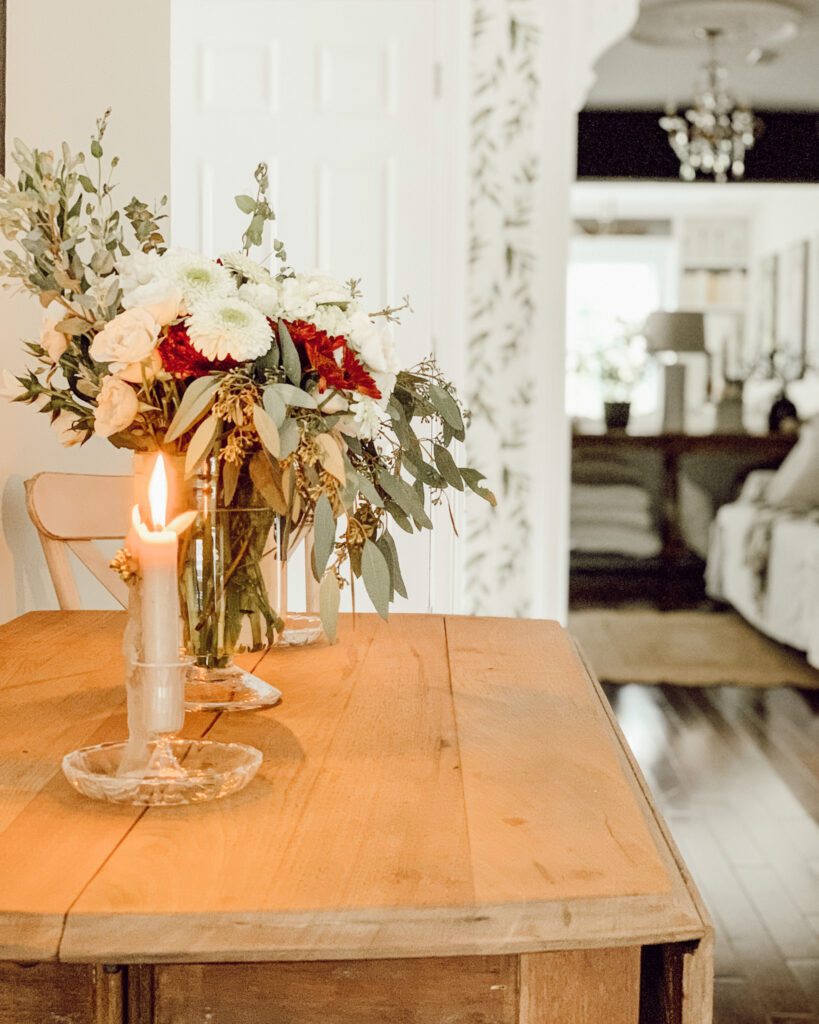 Fall flower arrangement for easy fall decor on a wooden kitchen table with a candle.