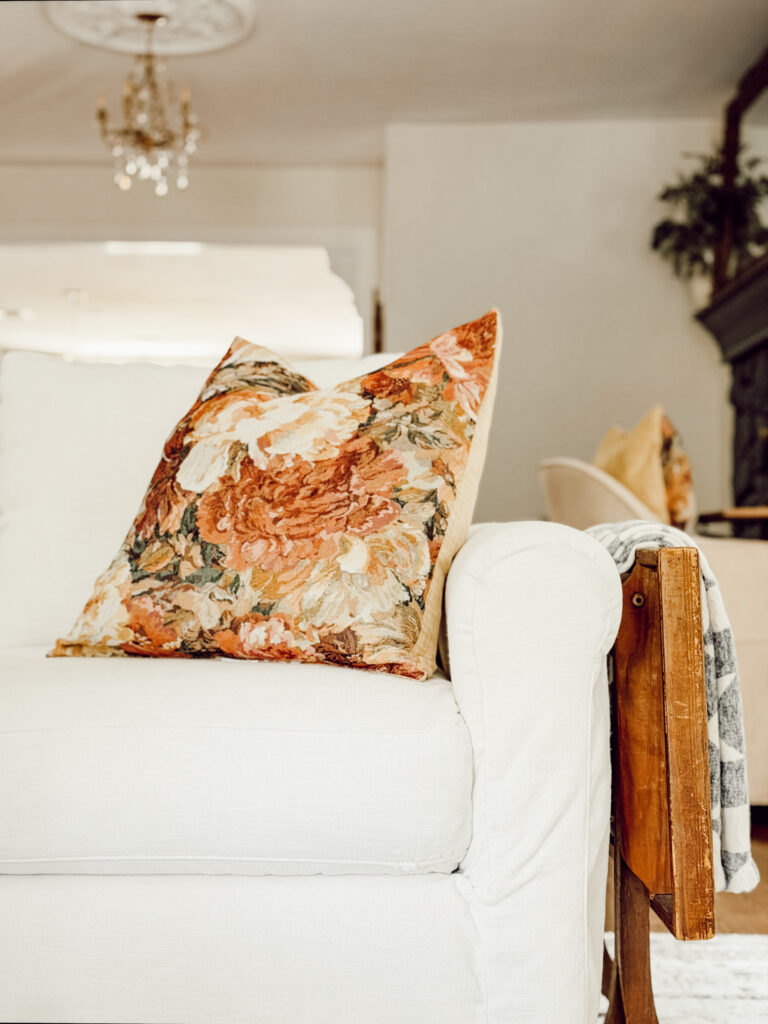 Fall throw pillow on a white living room couch for the autumn season.