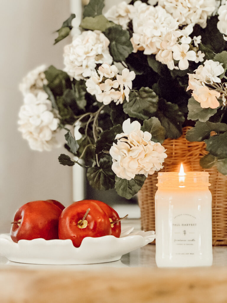Easy and quick fall kitchen decor ideas include red apples, fall flowers, and a scented candle.
