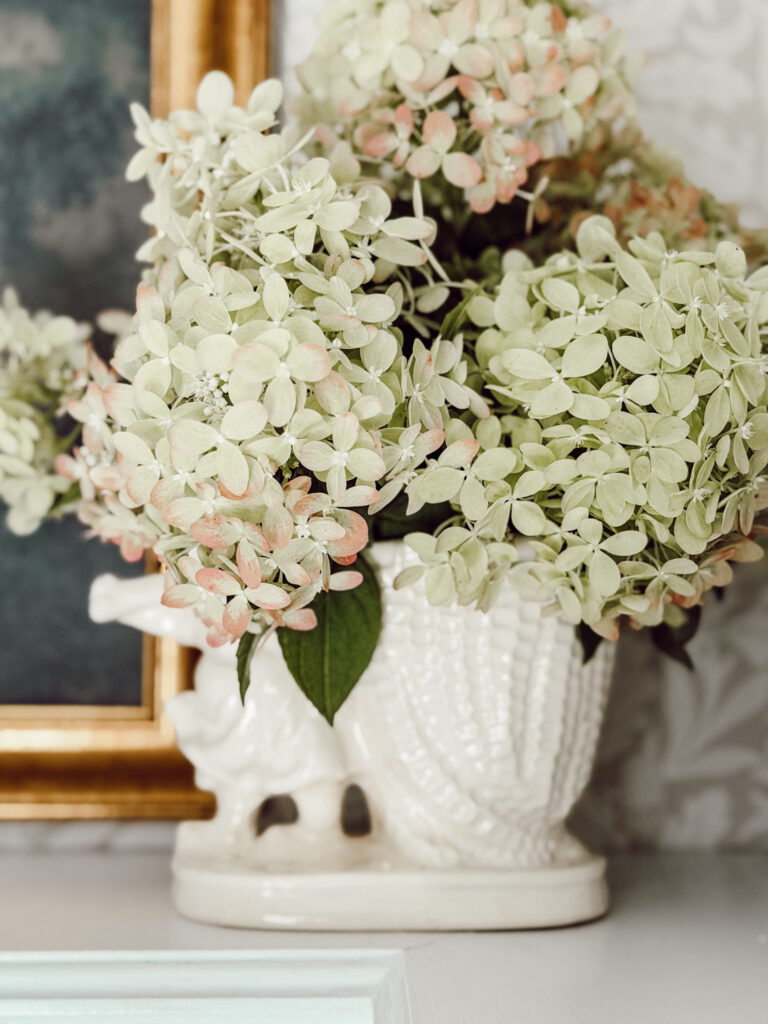 Hydrangeas in a vintage vase on an open shelf in the kitchen for quick fall decorating.
