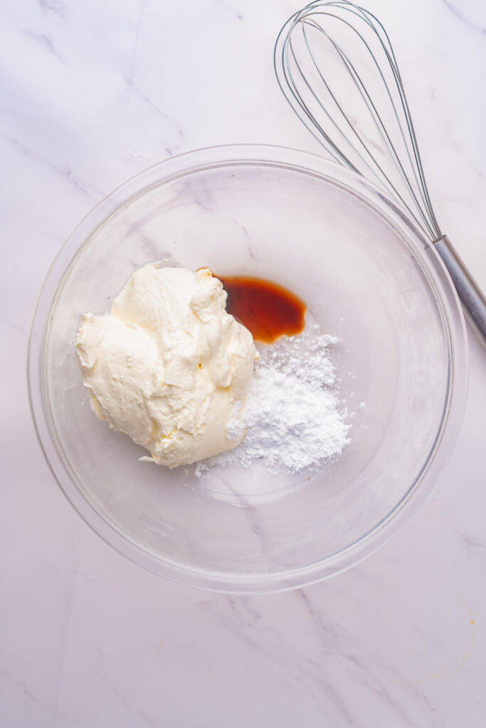 The simple ingredients like cream cheese, powdered sugar, and vanilla extract in a large mixing bowl.