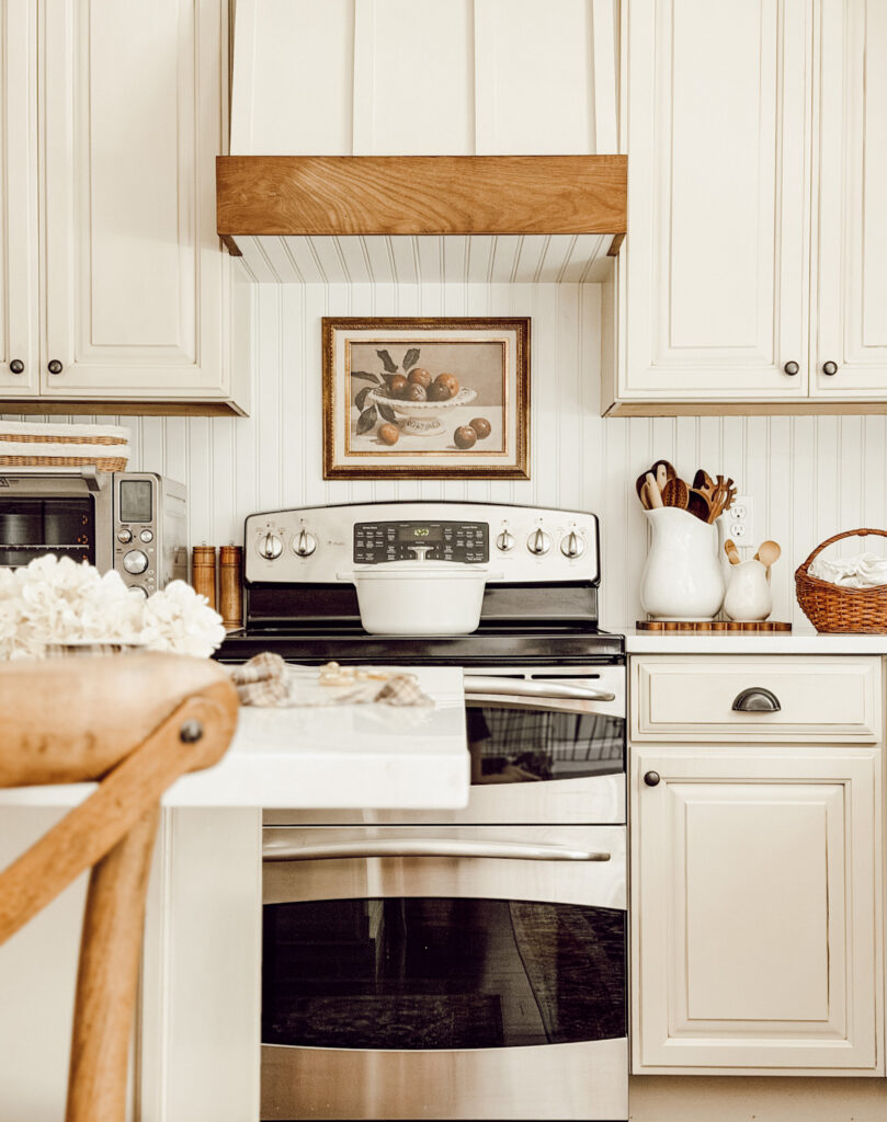 Update your home decor for fall with vintage artwork, a pitcher filled with wooden spoons, baskets, and faux fall flowers.