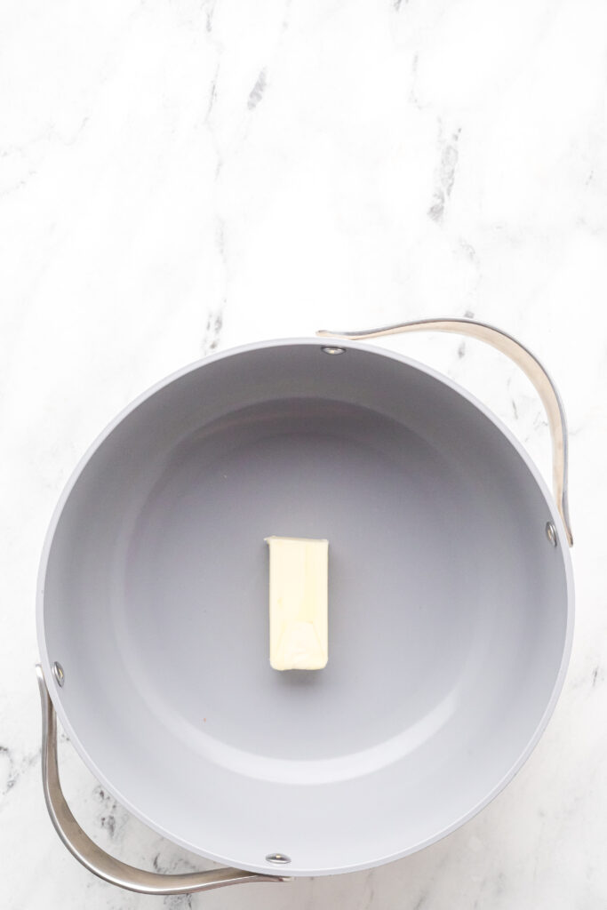 Place a stick of unsalted butter in a large pot to melt to make the rice cereal mixture.