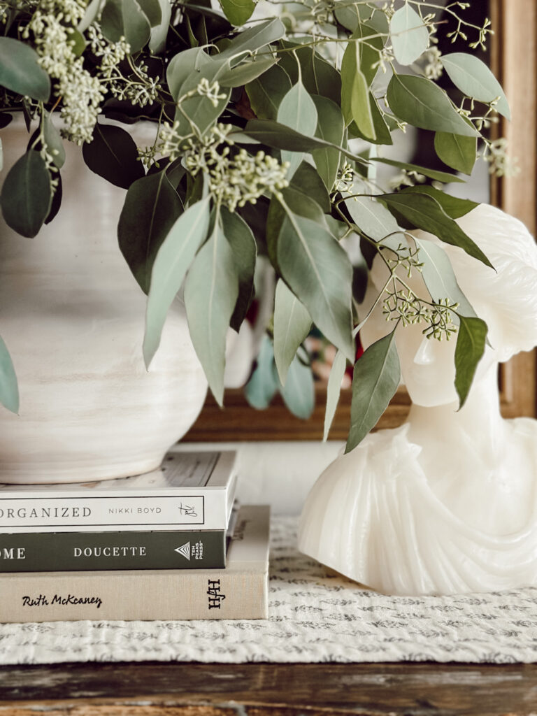 Weekly Wednesday Wish List #272 Eleanor Rose Home vase of eucalyptus and a bust candle with a stack of books.