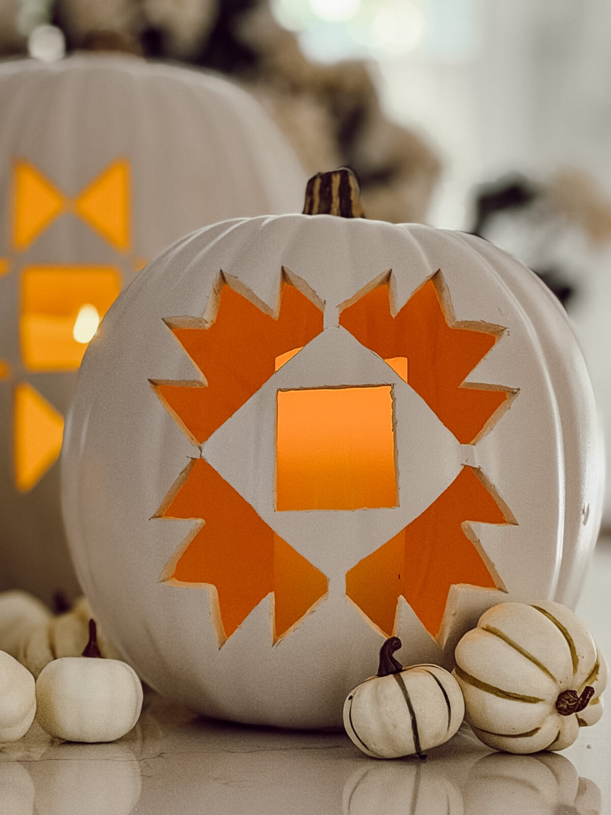 Carved pumpkin for fall decorating  on kitchen counter with other small pumpkins around the larger white pumpkin.