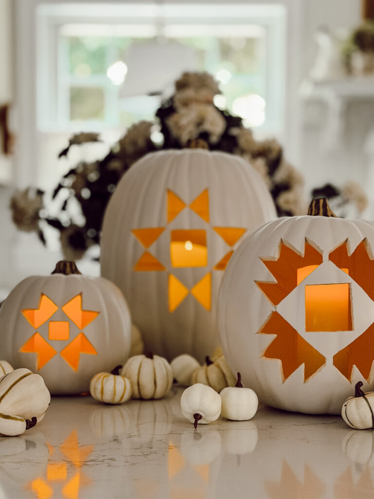 Quilt pattern carved faux pumpkins lit up with battery operated candles.